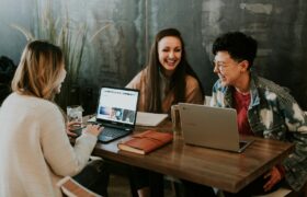 three people sitting in front of table laughing together
